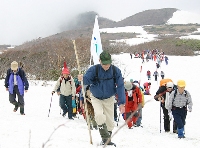残雪を踏みしめ山頂を目指す参加者