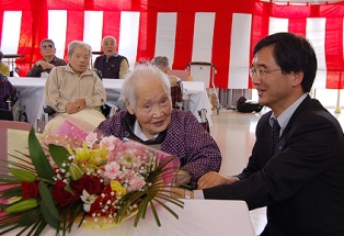 花束を贈られ笑顔の白石キヨシさん（左）