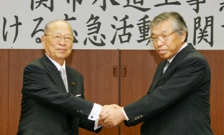 協定書に調印後、固い握手を交わす浅井市長（左）と小野寺理事長