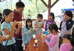 千厩高産業技術科の皆さんが講師を務めた「おもしろ科学実験」では手回し発電機や木炭、果物を使って電気を発生させました