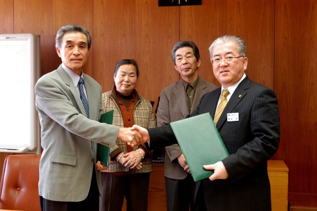 石川自治会長（左）と固く握手を交わす勝部市長（右）
