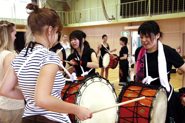 「タコモコタン～」のリズムの“渡り”の太鼓を大東校鹿踊部部員(右)に教わるドイツの学生(左)