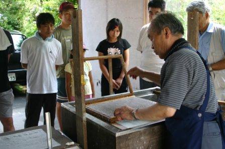 「紙すき館」の鈴木さんから昔ながらの紙すき方法を学ぶ参加者