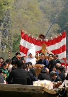 春の日差しを浴びる船上で親族らの祝福を受ける新郎新婦（中央）