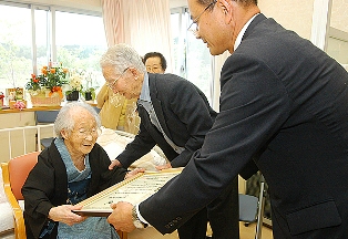 祝い状をにこやかに受け取る佐藤チウさん