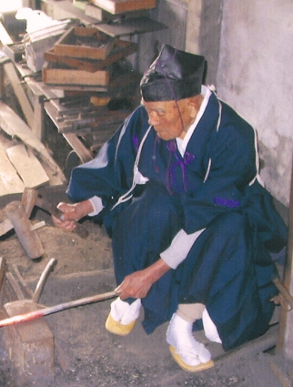 装束を身にまとい、工房で刀を鍛える菅原平さん（右）