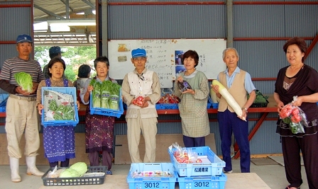 自慢の野菜を手にする組合員（右から２番目が千葉組合長）と朝一番のお客さん（右端）