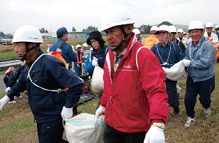 積み土のう工法には自主防災組織などの皆さんが取り組み。重い土のうを協力して運びました