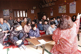 語り部（右手前）が方言を交えて物語る民話を楽しむ参加者