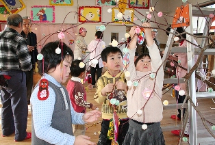 ミズキの枝に丁寧に飾り付ける園児たち