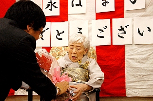 阿部保健福祉部長からの花束を受け取る冨永はま子さん