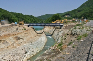 崩落した大量の土砂が磐井川をせき止めた市野々原地内の仮排水路。本復旧に向けて6月から仮排水路の拡幅工事が始まった。右側は国道342号（6月2日撮影）