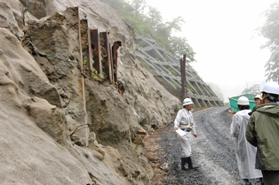 現在通行止めとなっている国道342号真湯ー須川高原温泉間の茂庭沢の大規模なのり面崩壊により道路が落下した現場。中央左寄りの鉄の構造物は以前の落石防止柵。斜面はモルタル吹き付けで仮復旧し工事中の崩落を抑えている（5月30日撮影）