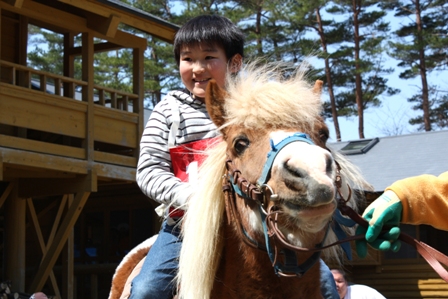 初めて乗るポニーに笑顔がこぼれる小学生