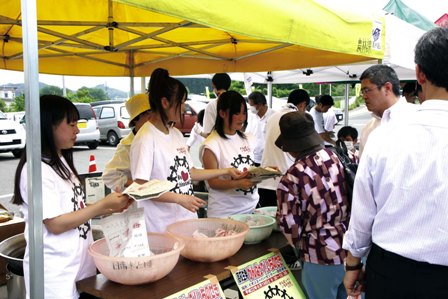 炊き出しで準備した袋入りのご飯を配る高校生