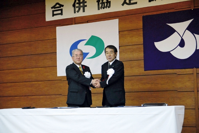 合併協定書に調印し、固い握手を交わす勝部市長と畠山博藤沢町長（右）