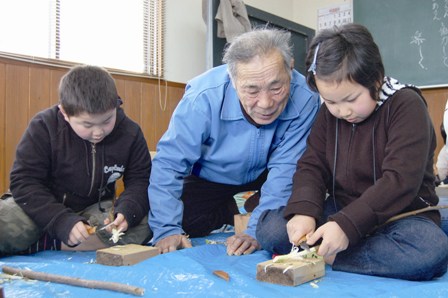 地元のお年寄りの手ほどきを受けながら作業する参加者たち