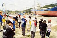 津波で打ち上げられた巻き網漁船「第18共徳丸」の前で黙祷する室根西小児童ら