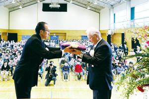 出席者が見守る中、戸田校長（左）から鈴木市教育委員長（右）に校旗が返納され、140年の歴史に幕が下ろされた 