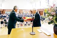 鈴木市教育委員長（右）に校旗を返納する新毛校長（左）