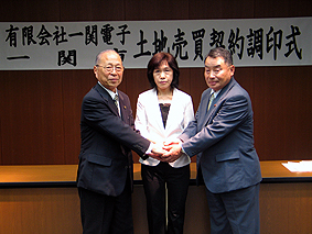 土地売買契約調印後握手を交わす（左から）浅井市長、近藤代表取締役、佐々木議長