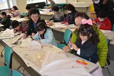 凧にイラストやメッセージを記入する親子